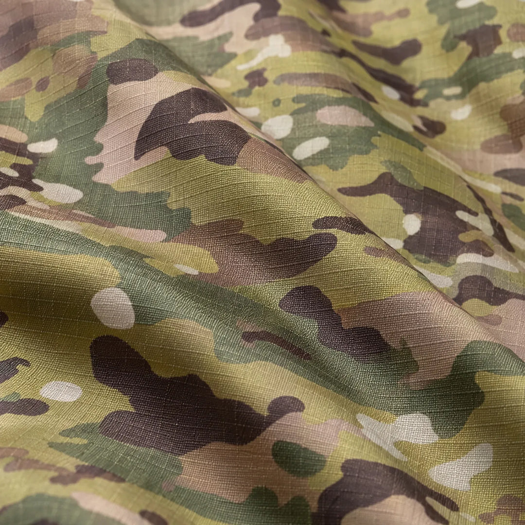 Close-up van de stof met groen-bruine camouflageprint, waarop de geweven ripstop-structuur en de plooien van het materiaal goed te zien zijn. 6