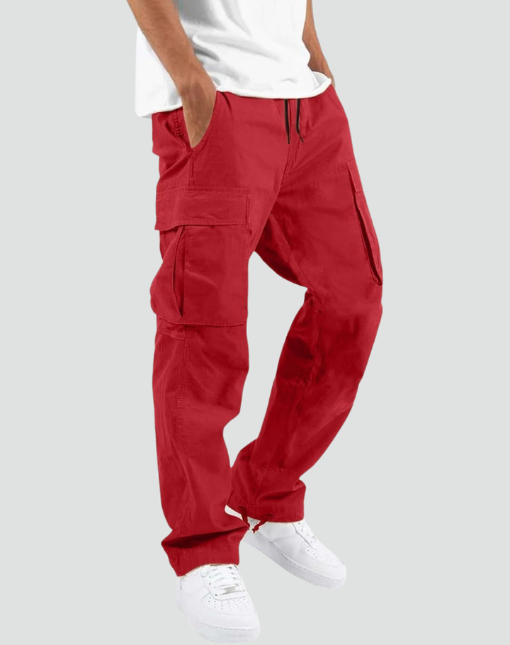 Model draagt rode cargobroek met handen in de zakken, zijzakken met klep en trekkoord, gecombineerd met wit T-shirt en witte sneakers. 10