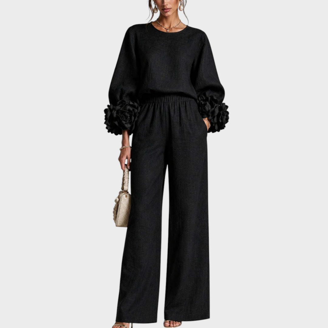 Model in zwarte set met grote bloemen aan de mouwboorden en wijde broek, vooraanzicht 3