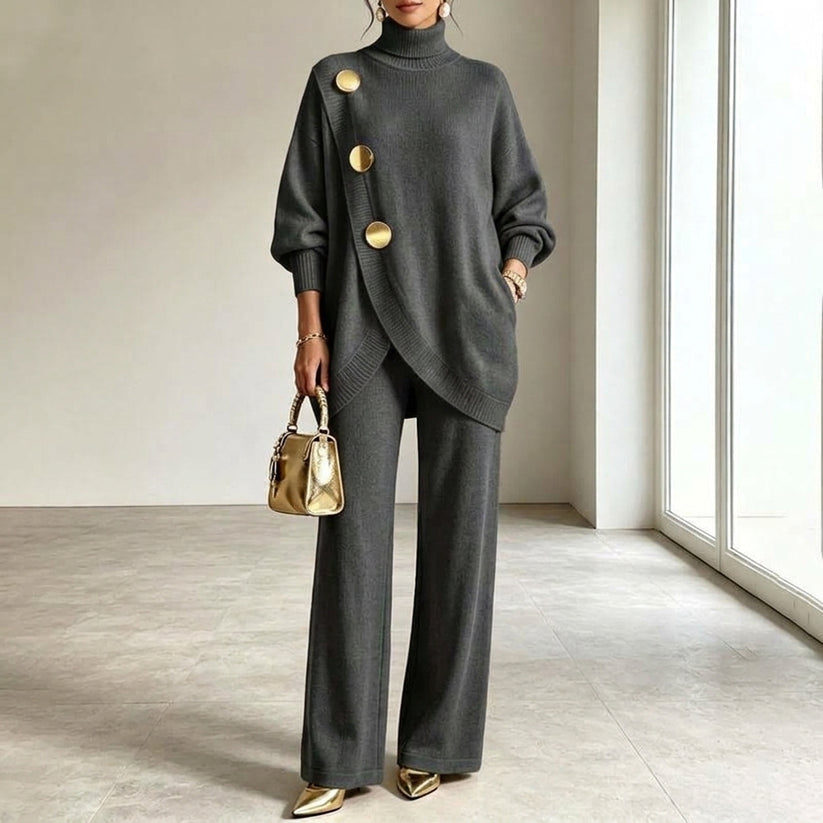 Gebreide set in donkergrijs, gedragen door een model met gouden handtas, asymmetrische top en wijde broek. 4