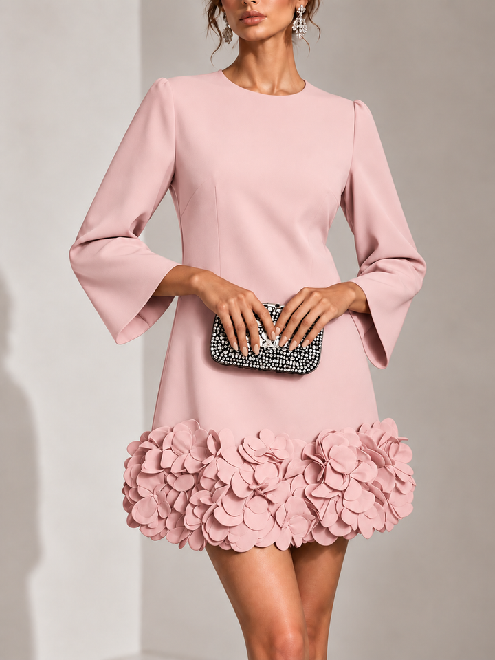 Roze jurk van voren gedragen, met clutch in beide handen en 3D-bloemen langs de zoom. 9