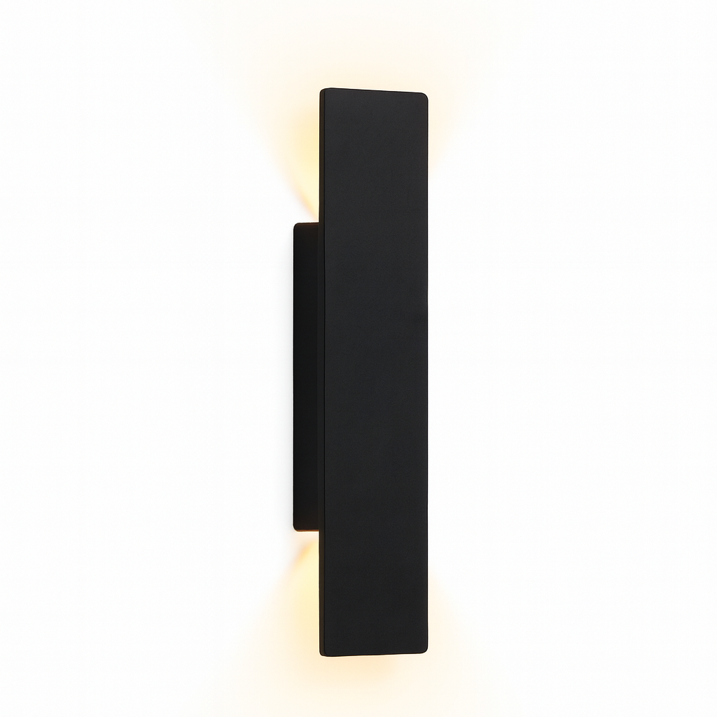 Zwarte rechthoekige wandlamp op witte achtergrond, schuin van opzij gezien, met warm licht dat boven en onder langs de muur schijnt. 1