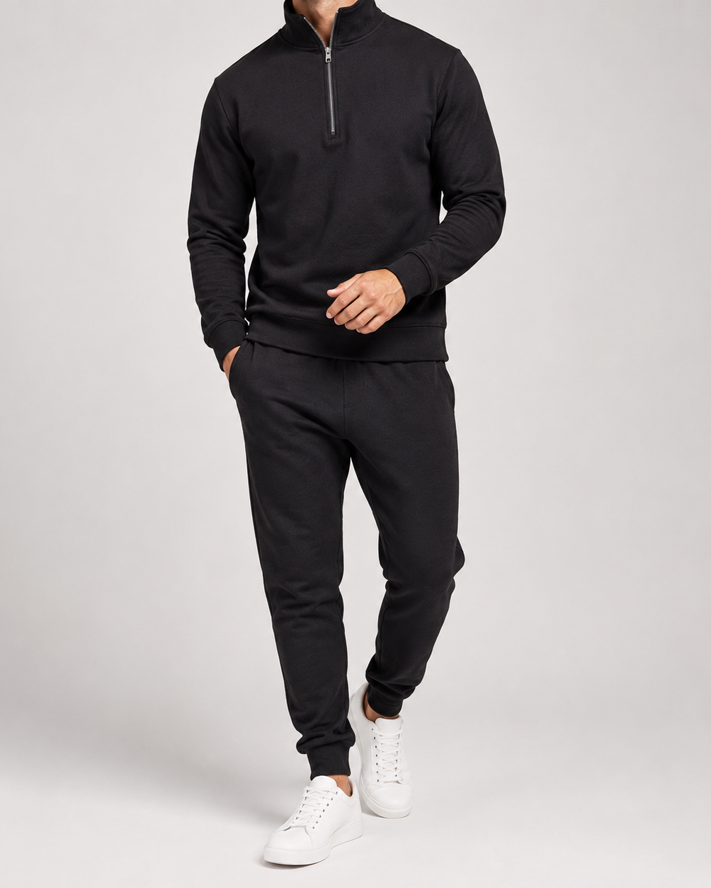 Model in zwart trainingspak met halve rits en joggingbroek, gedragen met witte sneakers 3