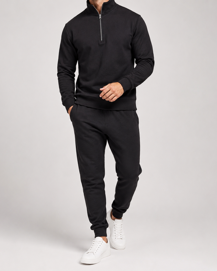 Model in zwart trainingspak met halve rits en joggingbroek, gedragen met witte sneakers 3