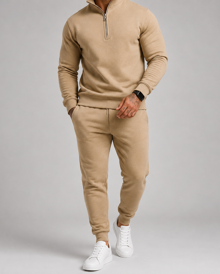 Model in beige trainingspak met halve rits, een smartwatch om de pols en witte sneakers 5