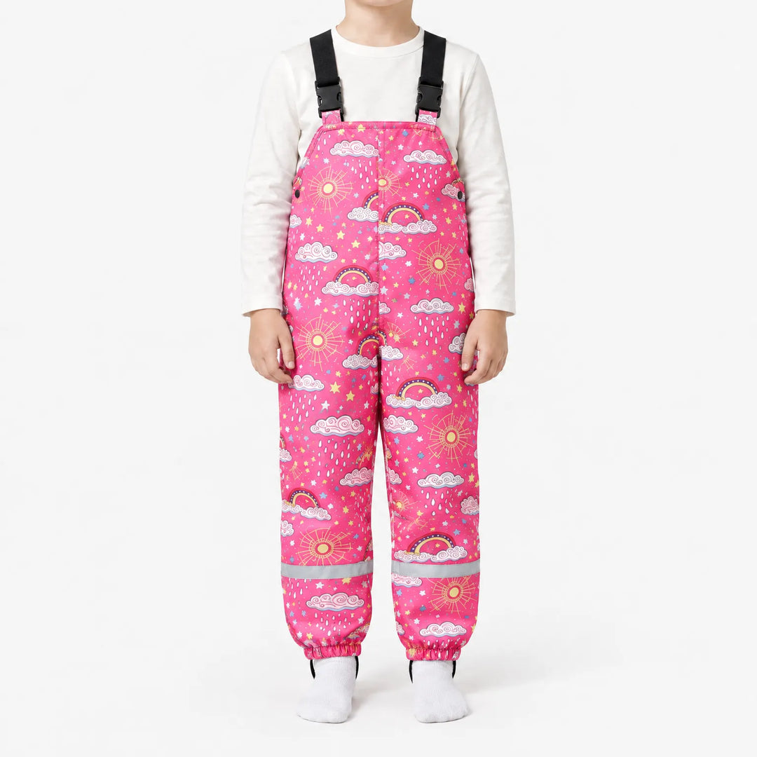 Kind draagt roze tuinbroek met wolken, regendruppels, zonnetjes en regenbogen, met reflecterende strepen aan de pijpen. 10