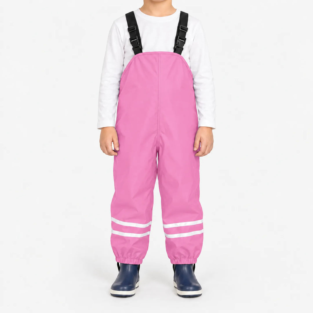 Kind draagt lichtroze tuinbroek met reflecterende banden en elastische enkelbanden, met wit shirt en donkerblauwe laarsjes. 13