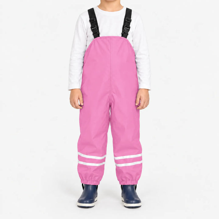 Kind draagt lichtroze tuinbroek met reflecterende banden en elastische enkelbanden, met wit shirt en donkerblauwe laarsjes. 13