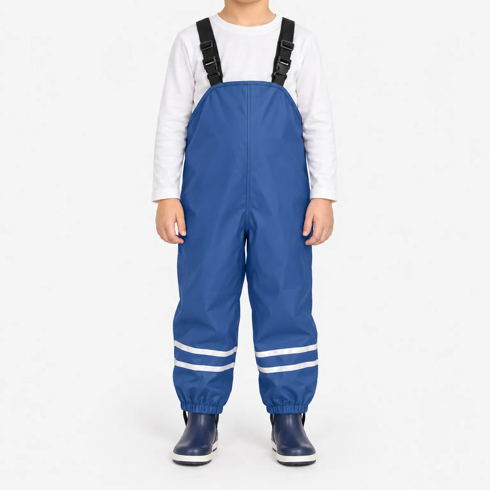 Kind draagt blauwe tuinbroek met reflecterende banden en elastische enkelbanden, gecombineerd met wit shirt en donkerblauwe laarzen, op witte achtergrond. 2
