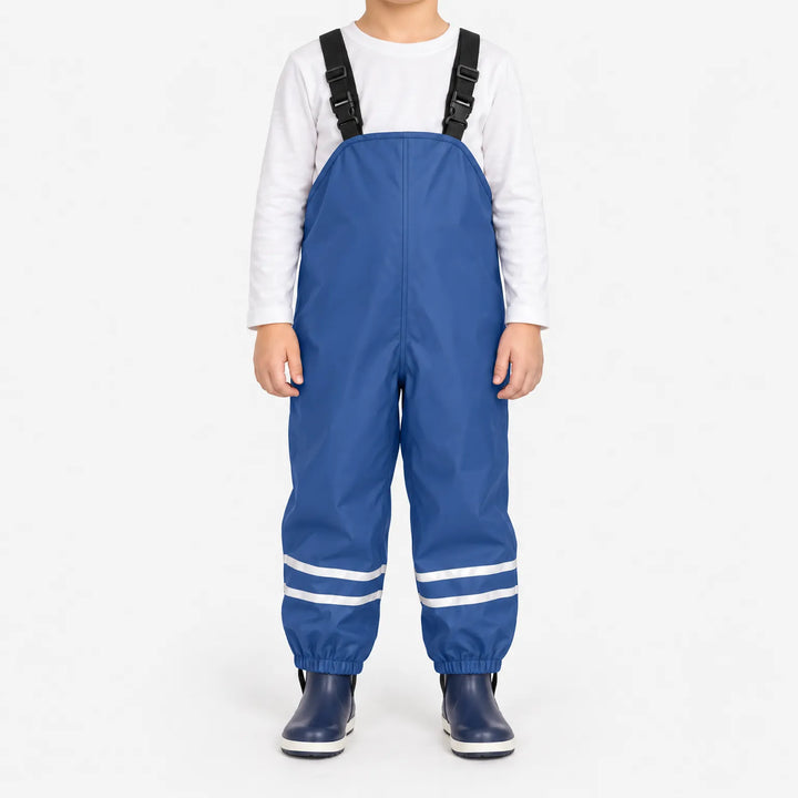 Kind draagt blauwe tuinbroek met reflecterende banden en elastische enkelbanden, gecombineerd met wit shirt en donkerblauwe laarzen, op witte achtergrond. 2