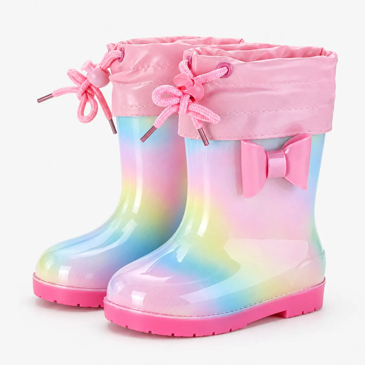 Paar regenboogkleurige laarzen met roze strik en een roze stoffen schachtrand met trekkoord en strikjes. 10