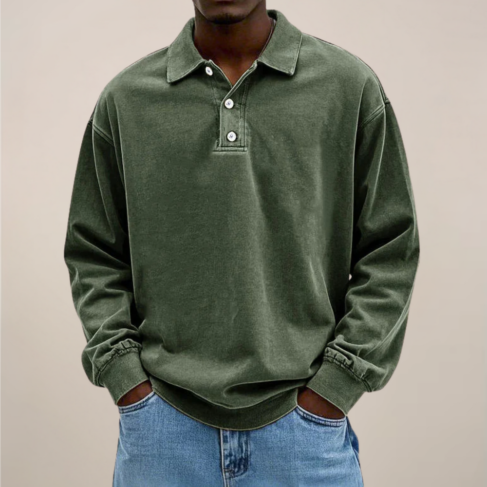 Model draagt het poloshirt in legergroen, voorkant met knoopsluiting en kraag, handen in de zakken van een spijkerbroek. 2