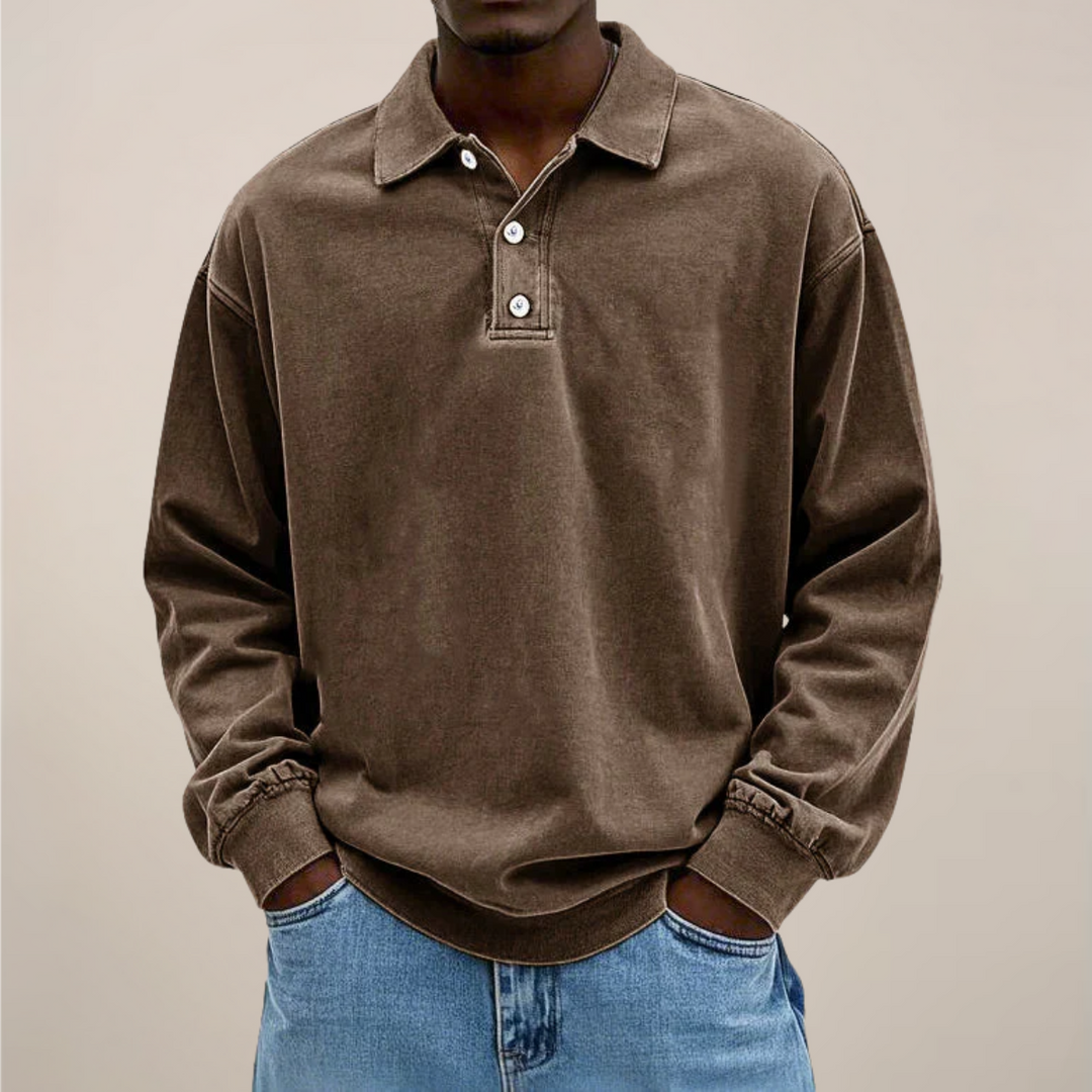 Model draagt het poloshirt in bruin, voorkant met knoopsluiting, lange mouwen met boord en een spijkerbroek. 3