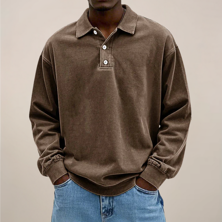Model draagt het poloshirt in bruin, voorkant met knoopsluiting, lange mouwen met boord en een spijkerbroek. 3