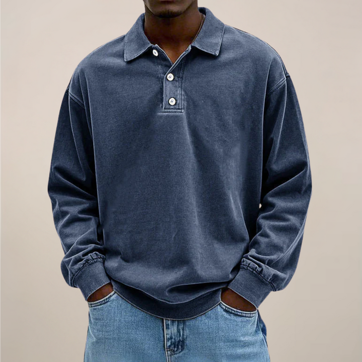 Model draagt het poloshirt in donkerblauw, voorkant met knoopsluiting, losvallende lange mouwen en handen in de broekzakken. 5
