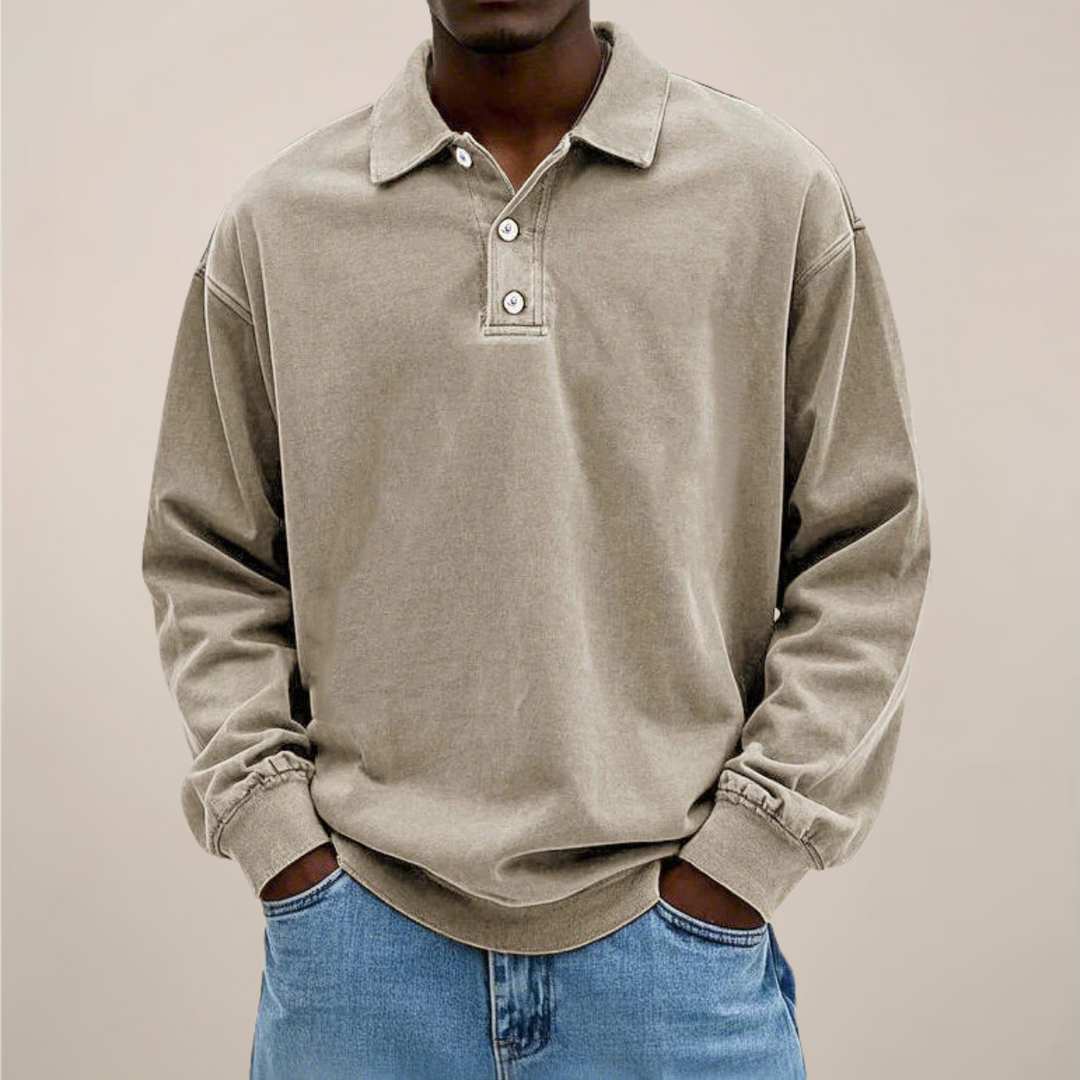 Model draagt het poloshirt in beige, voorkant met kraag en knoopsluiting, ruime pasvorm gecombineerd met een spijkerbroek. 6