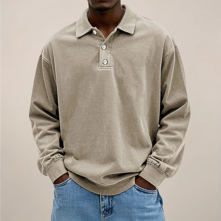 Model draagt het poloshirt in beige, voorkant met kraag en knoopsluiting, ruime pasvorm gecombineerd met een spijkerbroek. 6