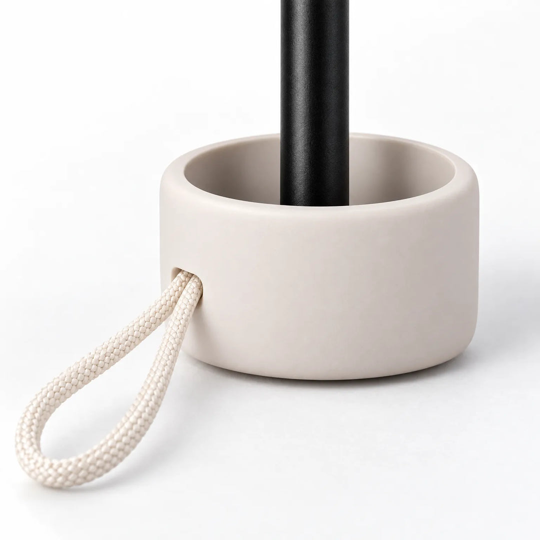 Close-up van het handvat van de paraplu: een beige kapje rond de zwarte steel met een gevlochten crèmekleurig koordlusje. 5