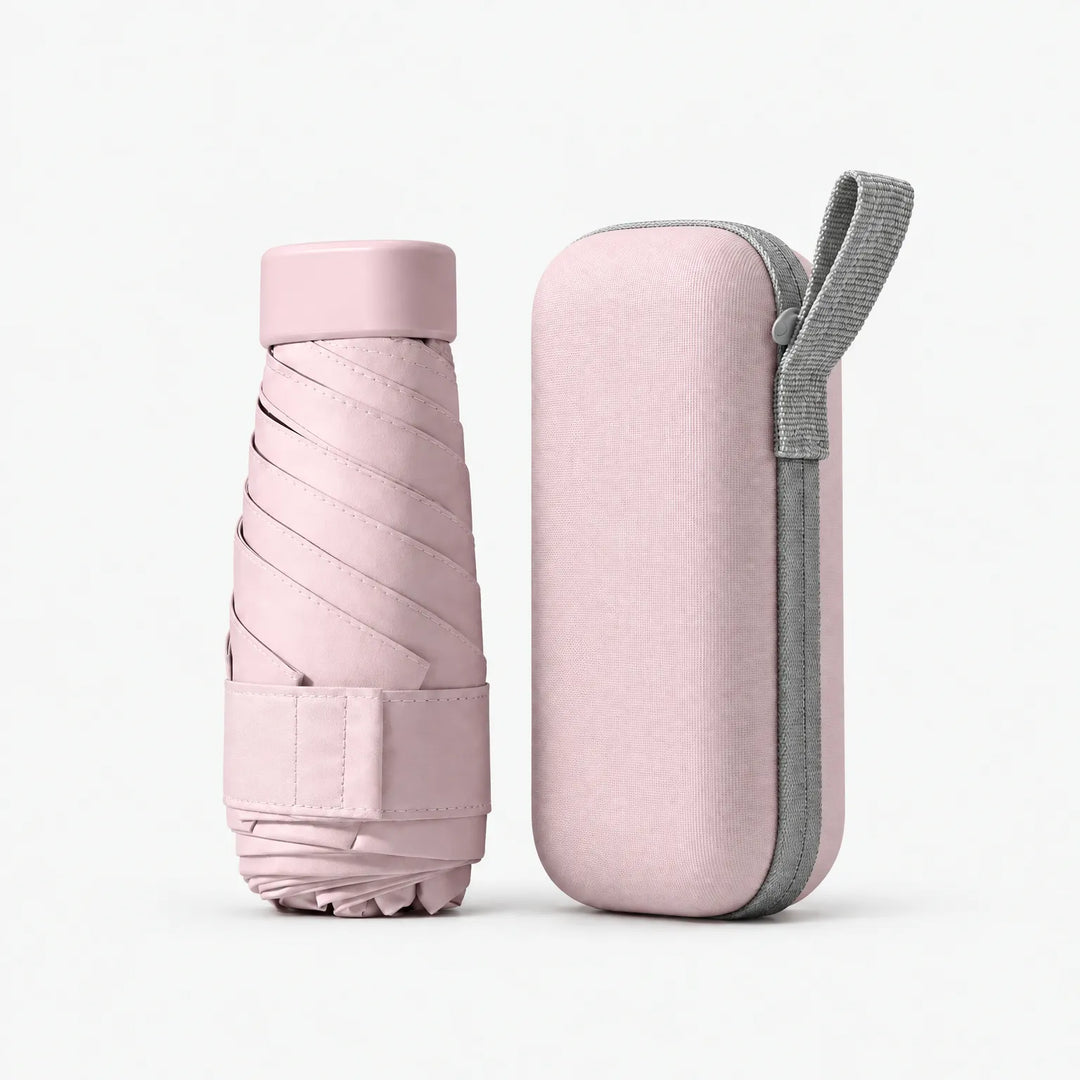 Dichtgevouwen roze paraplu naast het roze etui met grijs polsbandje en rits. 9