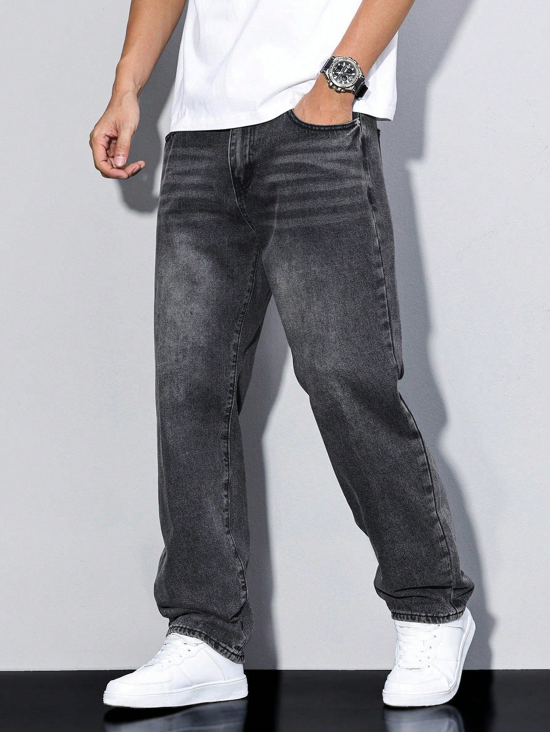 Donkergrijze gewassen jeans frontaal gedragen, ruime rechte pijpen, wit t-shirt en witte sneakers. 10