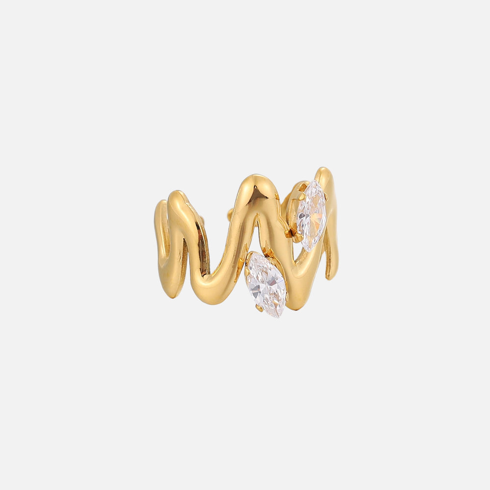 Zijaanzicht van de goudkleurige ring met sculpturale golvende lijnen en twee glinsterende heldere stenen op een effen lichte achtergrond. 2