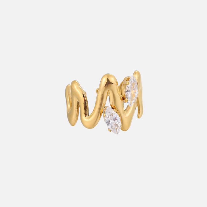 Zijaanzicht van de goudkleurige ring met sculpturale golvende lijnen en twee glinsterende heldere stenen op een effen lichte achtergrond. 2