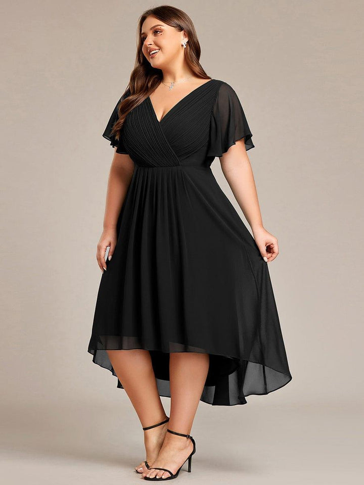 Zwarte jurk in zijaanzicht op een curvy model, met licht opgetilde rok die de hoog-laagzoom toont. 29