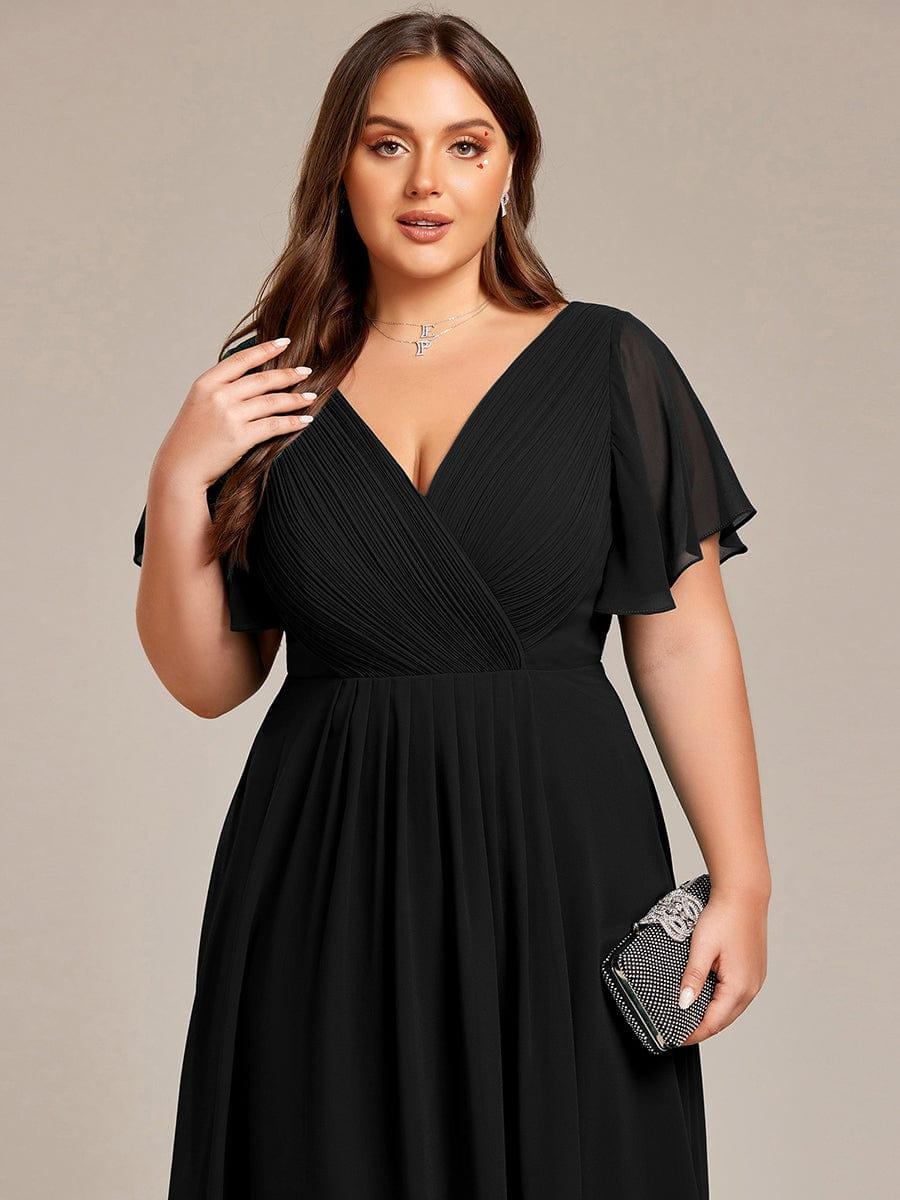 Close-up van het V-halsbovenstuk in zwart op een curvy model, met een glinsterend avondtasje in de hand. 28