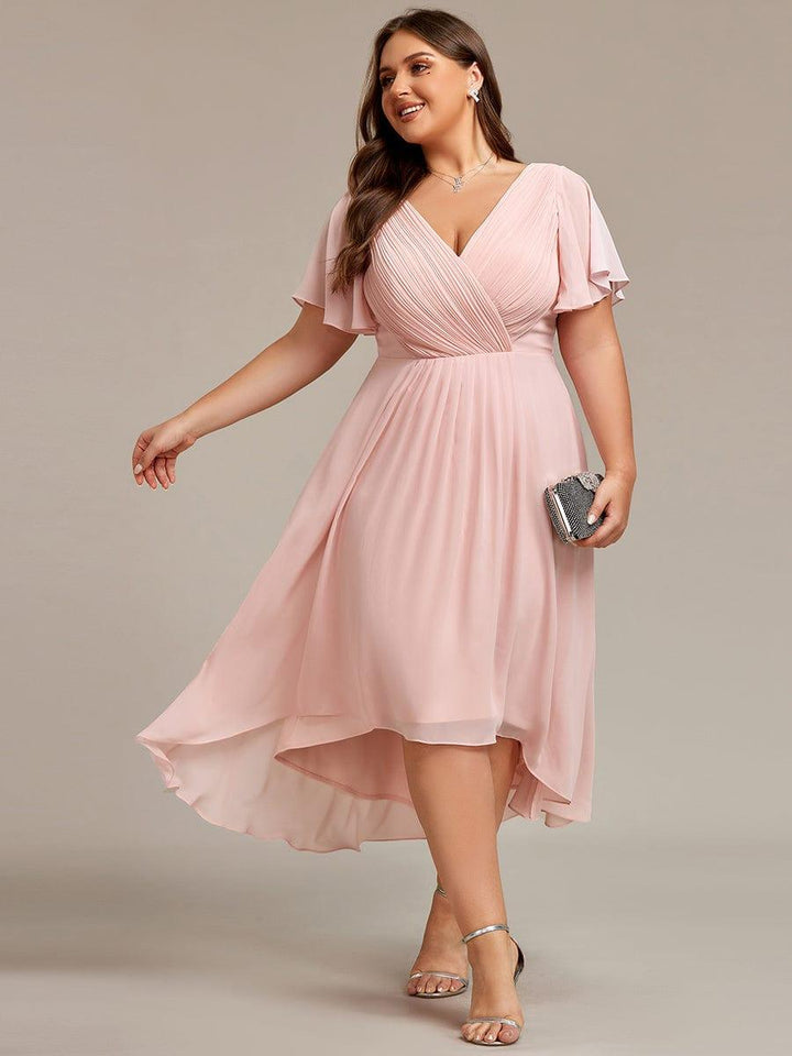 Lichtroze versie van de chiffon jurk op een curvy model, met zilverkleurige sandalen en een glinsterend tasje. 31