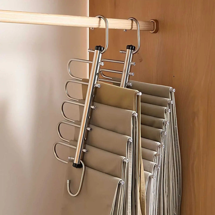 Twee metalen hangers met vijf lagen aan de kastroede, volledig uitgeklapt en behangen met broeken in beige tinten. 4
