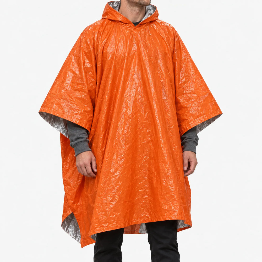 Man draagt de oranje poncho met capuchon van voren, zodat de glimmerende, gekreukelde buitenkant en zilverkleurige binnenkant zichtbaar zijn. 2