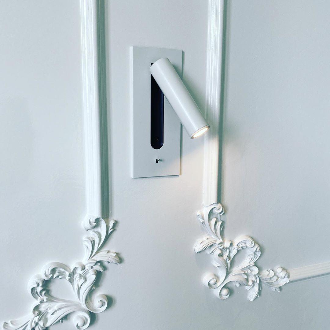 Witte wandlamp ingebouwd in een witte muur met sierlijsten, de ledspot werpt licht langs de lijst 27