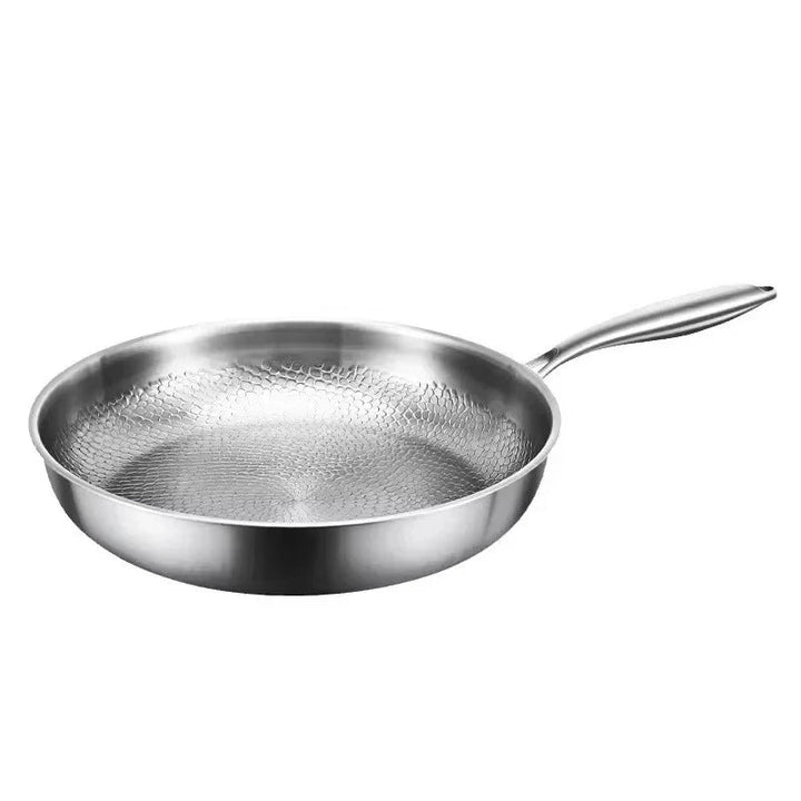 Zilverkleurige koekenpan met gehamerd honingraatpatroon in de bodem en een metalen steel, losgesneden op een witte achtergrond. 1