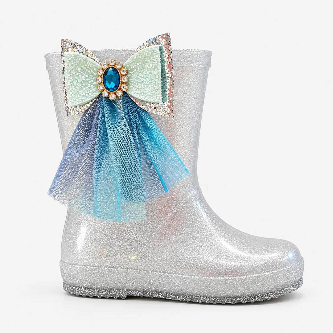 Zijaanzicht van een zilverkleurige glitterlaars met grote strik, blauwe edelsteen en hangend blauw tule lint. 4
