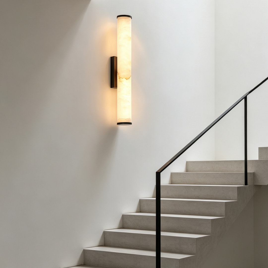 Verlichte marmeren wandlamp op een witte trapmuur naast een trap met zwarte leuning. 7