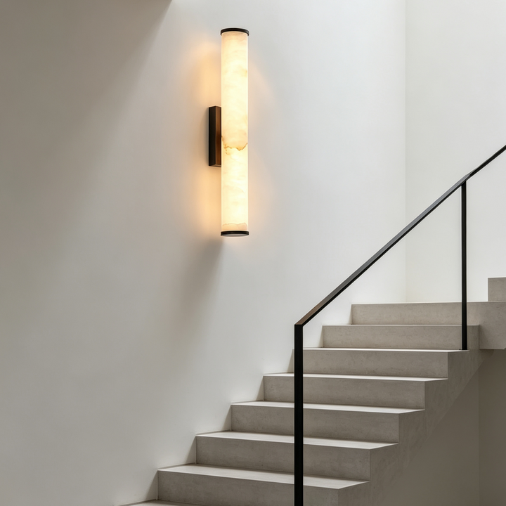 Verlichte marmeren wandlamp op een witte trapmuur naast een trap met zwarte leuning. 7