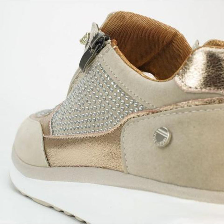 Close-up van de achterkant en zijkant van een beige sneaker met rits, steentjes, metallic hielstuk en bruine voering. 9