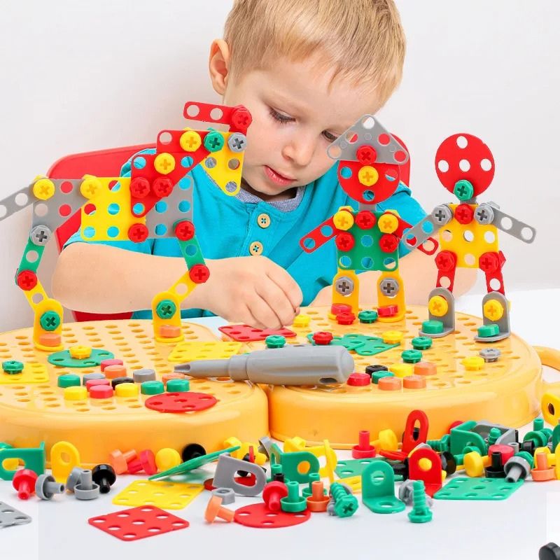 Jongetje bouwt aan een tafel drie kleurrijke robotfiguren van plaatjes en schroeven op de gele bouwplaten, met een schroevendraaier ertussen. 2