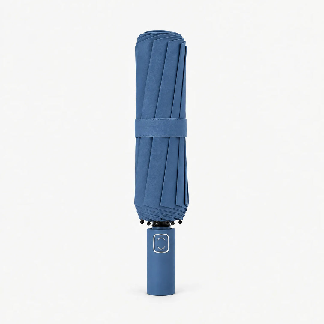 Dichtgevouwen blauwe paraplu met bandje, rechtopstaand op een witte achtergrond, handgreep onderaan. 11