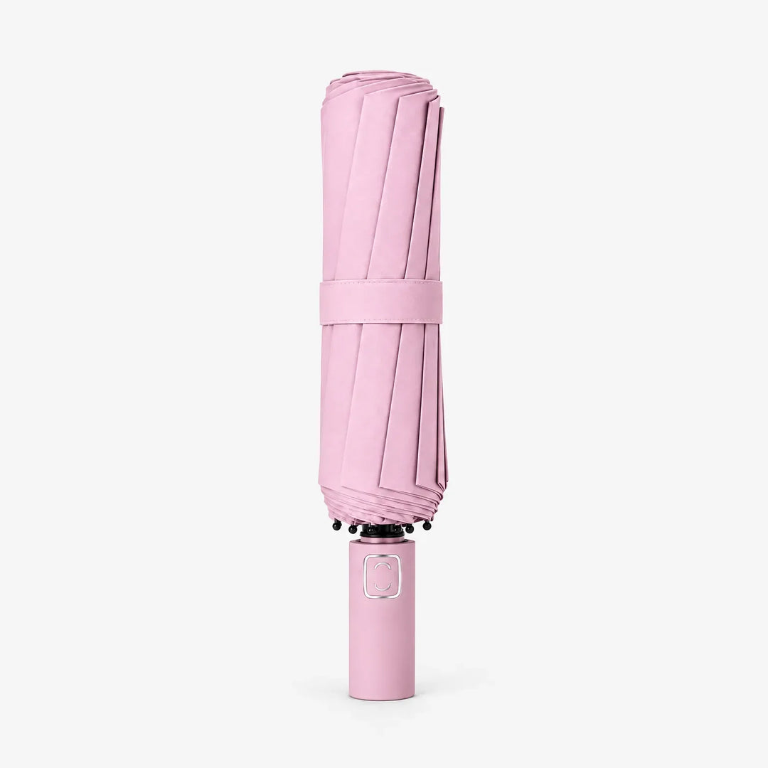 Dichtgevouwen roze paraplu met bandje, rechtopstaand op een witte achtergrond, handgreep onderaan. 7