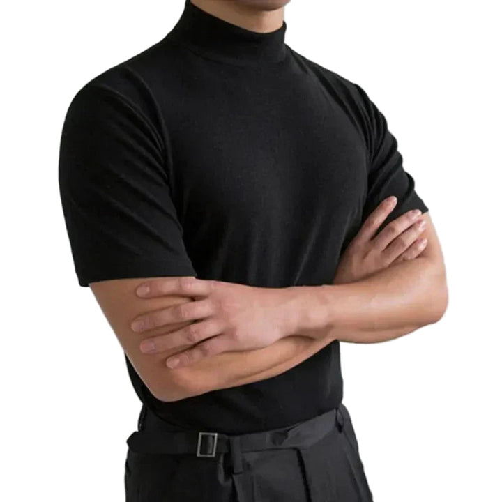 Zwart shirt met korte mouwen en opstaande hals, gedragen door een model met gekruiste armen, vrijgesteld op witte achtergrond. 1