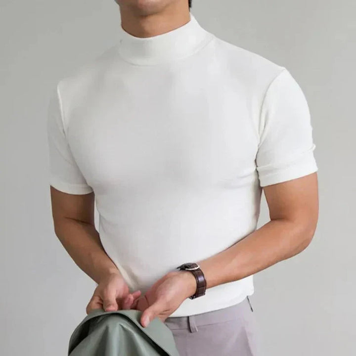 Wit shirt met opstaande hals en korte mouwen, gedragen door een model met horloge en een lichte broek, jasje in de hand. 4