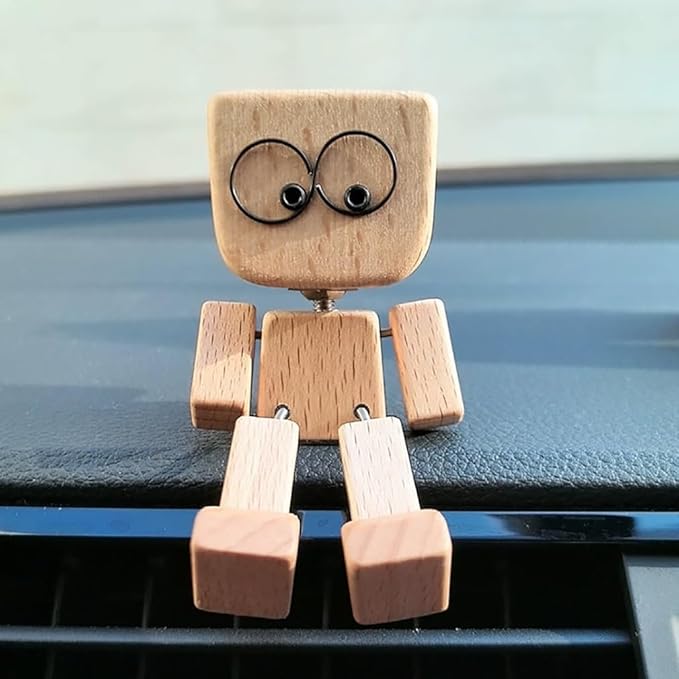 Vooraanzicht van het houten figuurtje met grote ronde ogen, de benen over de rand van een dashboard hangend. 4