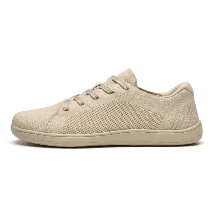 Beige mesh sneaker van opzij op een witte achtergrond, met elastische veters en een egale beige zool. 1