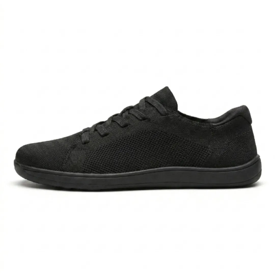 Zwarte mesh sneaker van opzij op een witte achtergrond, met zwarte veters en een zwarte zool. 10