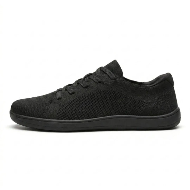 Zwarte mesh sneaker van opzij op een witte achtergrond, met zwarte veters en een zwarte zool. 10