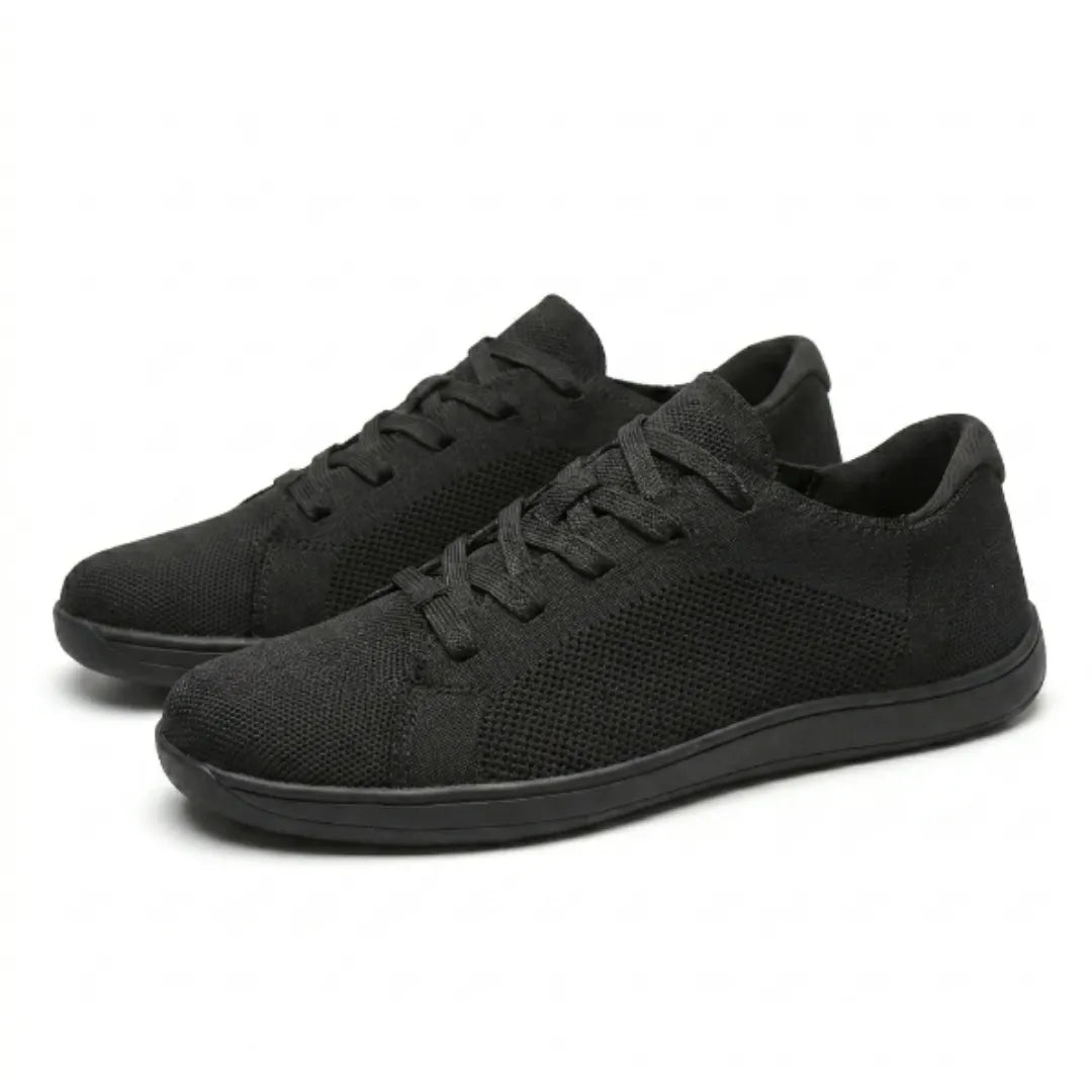 Twee zwarte mesh sneakers schuin van voren op een witte achtergrond, met veters en een zwarte zool. 16