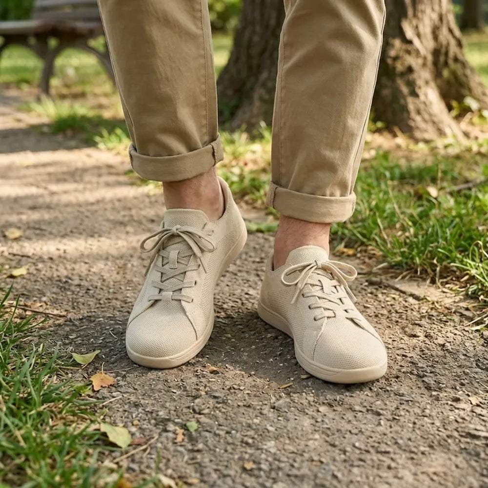 Beige sneakers gedragen door iemand in een khaki broek met omgeslagen pijpen, wandelend op een bospad. 2
