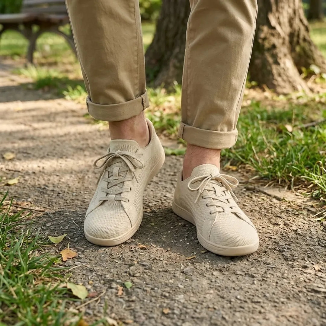 Beige sneakers gedragen door iemand in een khaki broek met omgeslagen pijpen, wandelend op een bospad. 2