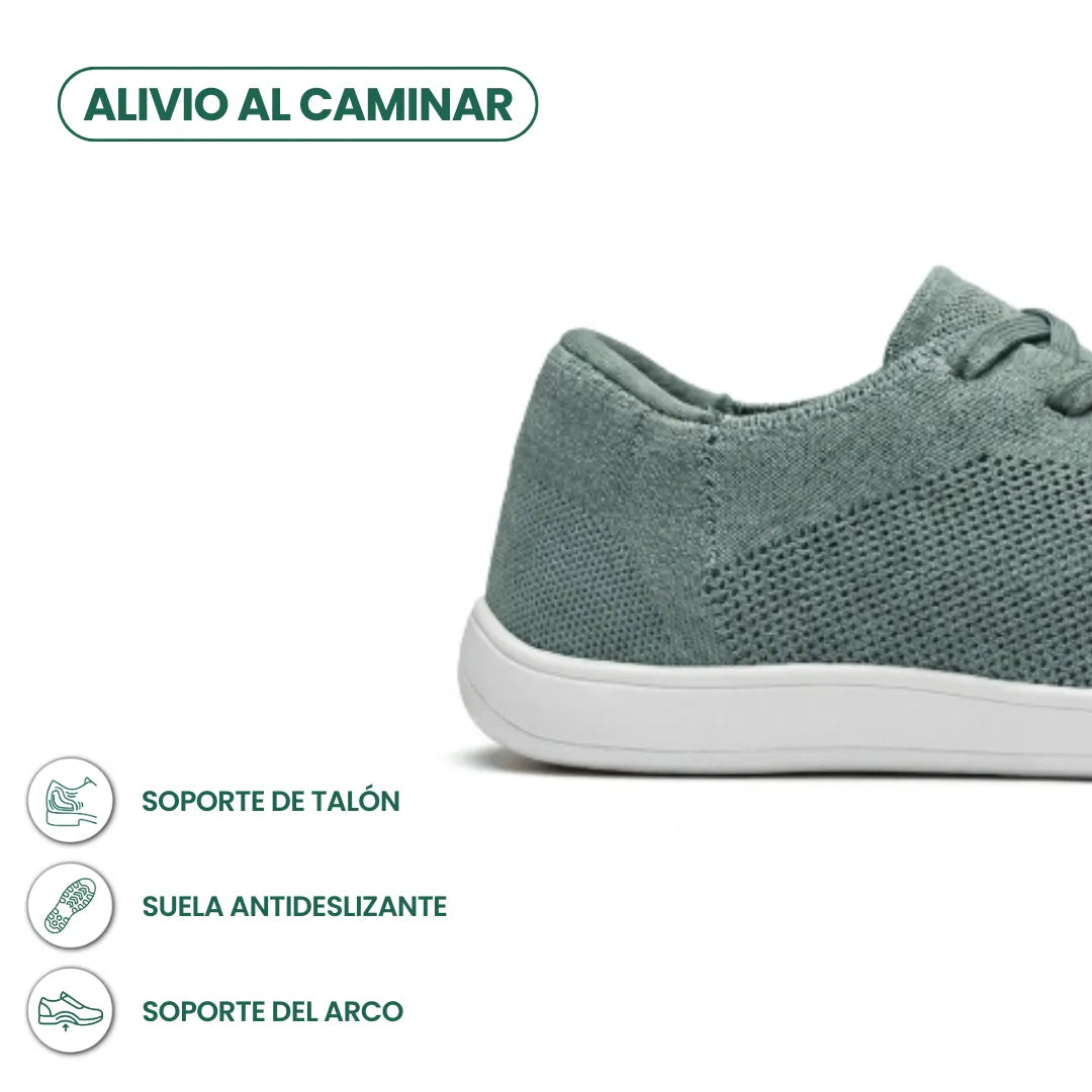 Close-up van de hiel van de saliegroene sneaker met witte zool, met pictogrammen voor hielondersteuning, antislipzool en booggewelfsteun. 31